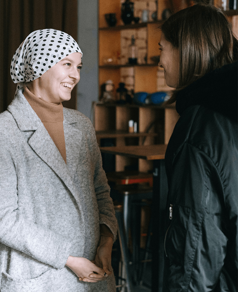 Two women chatting, one of them is wearing a head covering.